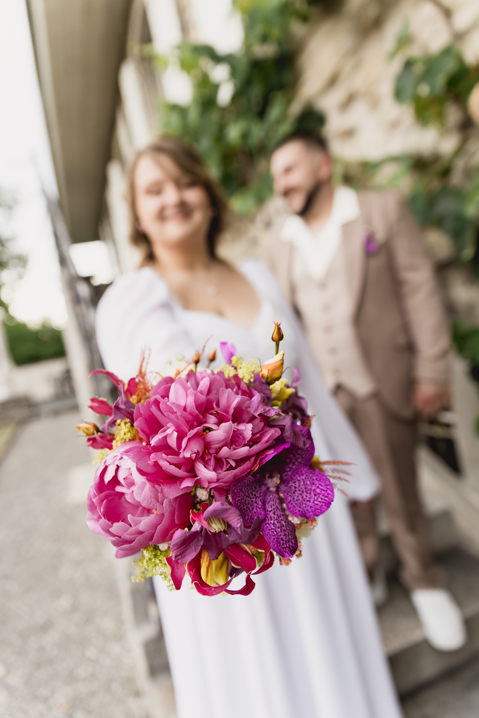 Bouquet rose au premier plan devant les mariés